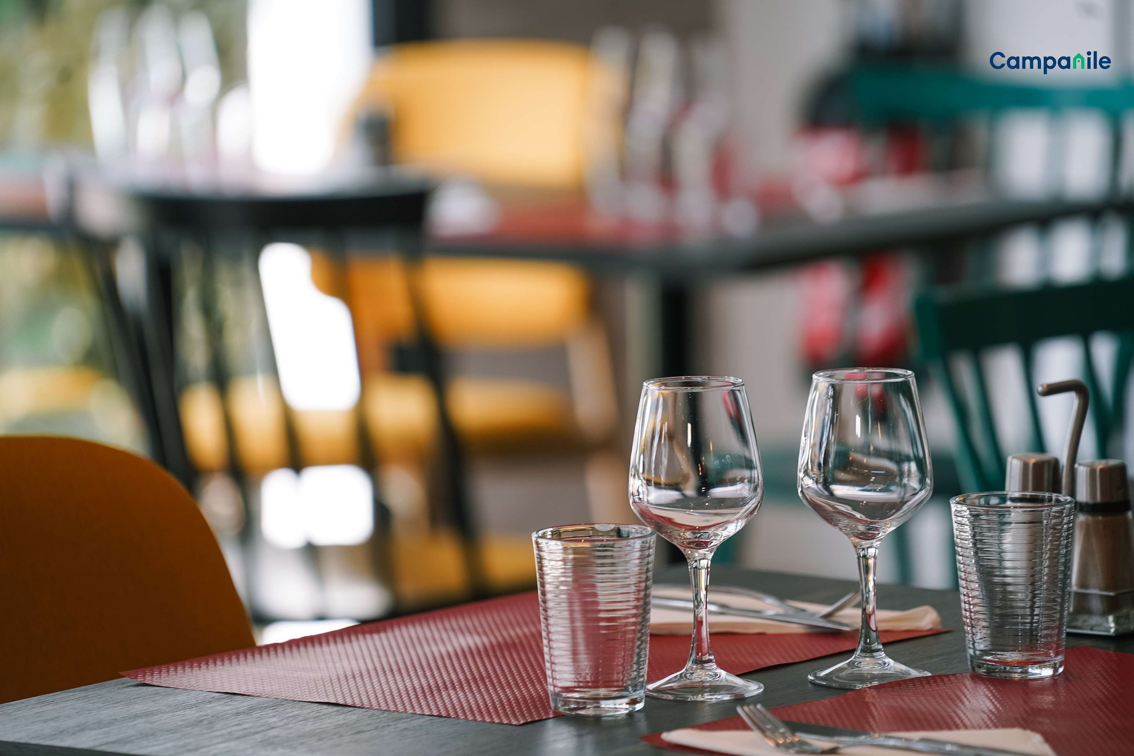 Una mesa con cuatro vasos y una botella, sobre un mantel individual rojo.