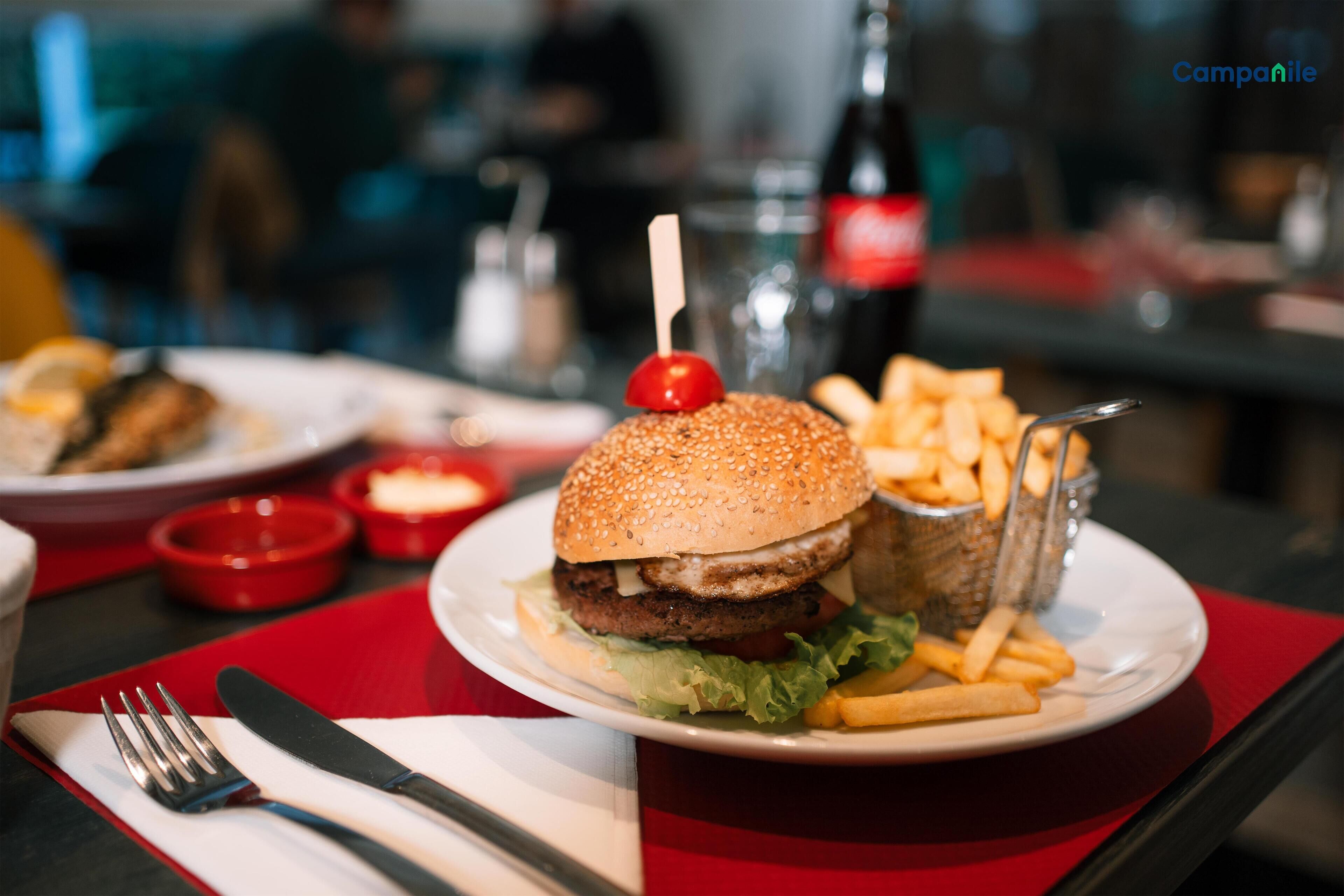 A meal with a burger, fries, and a drink on a red table.