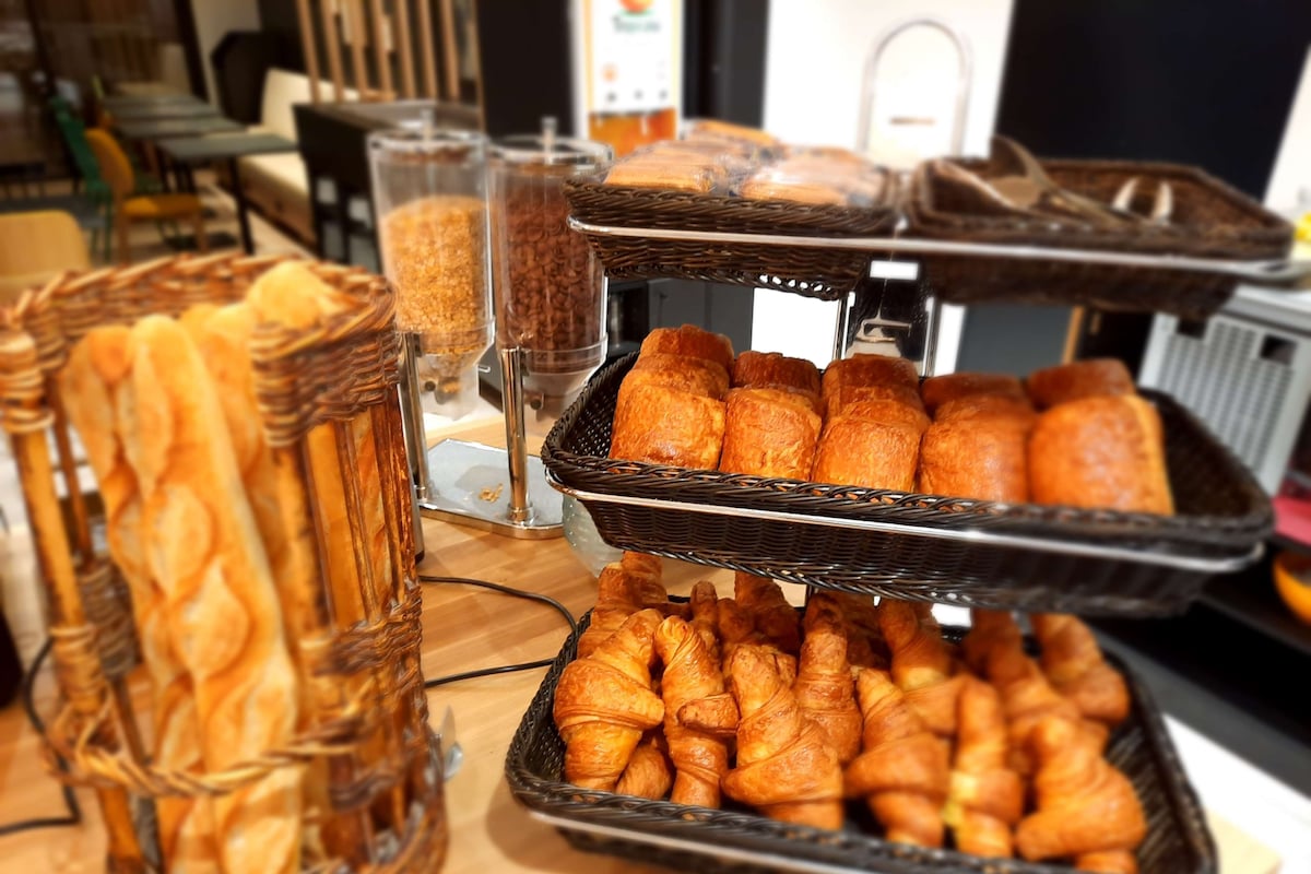 A bakery display with various baked goods, including bread and pastries, arranged on trays and baskets.