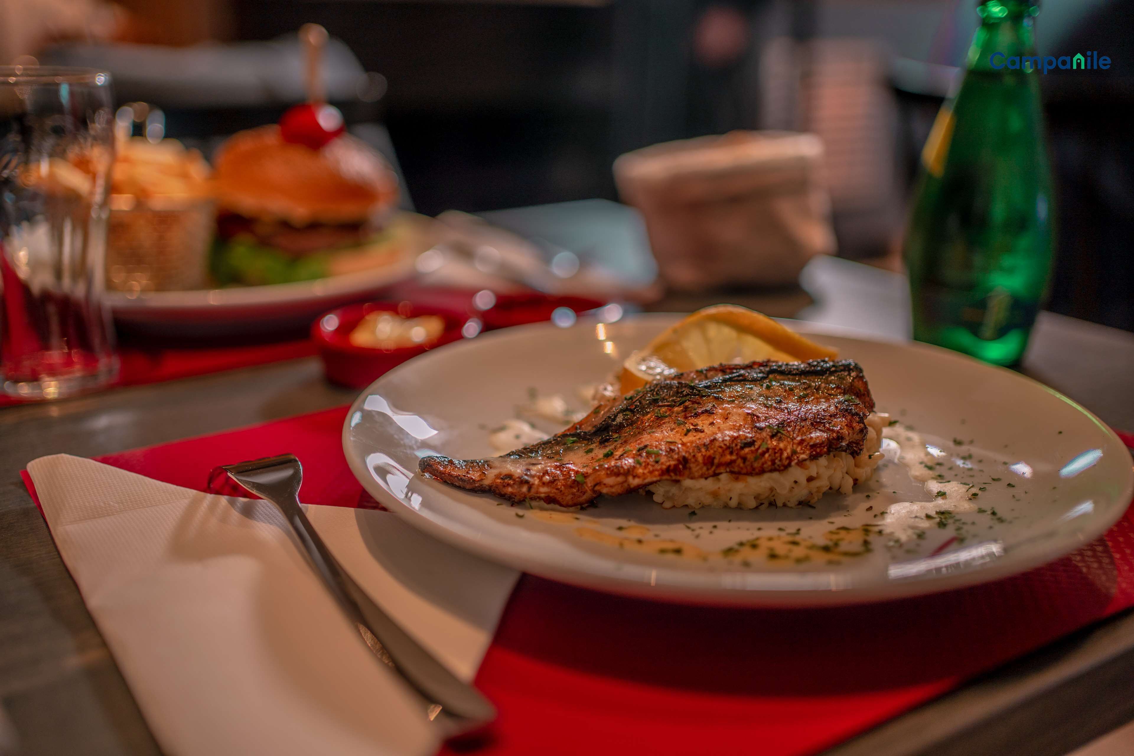 Un plato con pescado a la parrilla y arroz, un tenedor y una servilleta sobre una mesa.