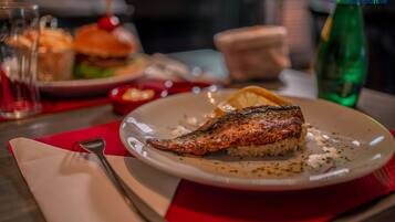 Un plato con pescado a la parrilla y arroz, un tenedor y una servilleta sobre una mesa.
