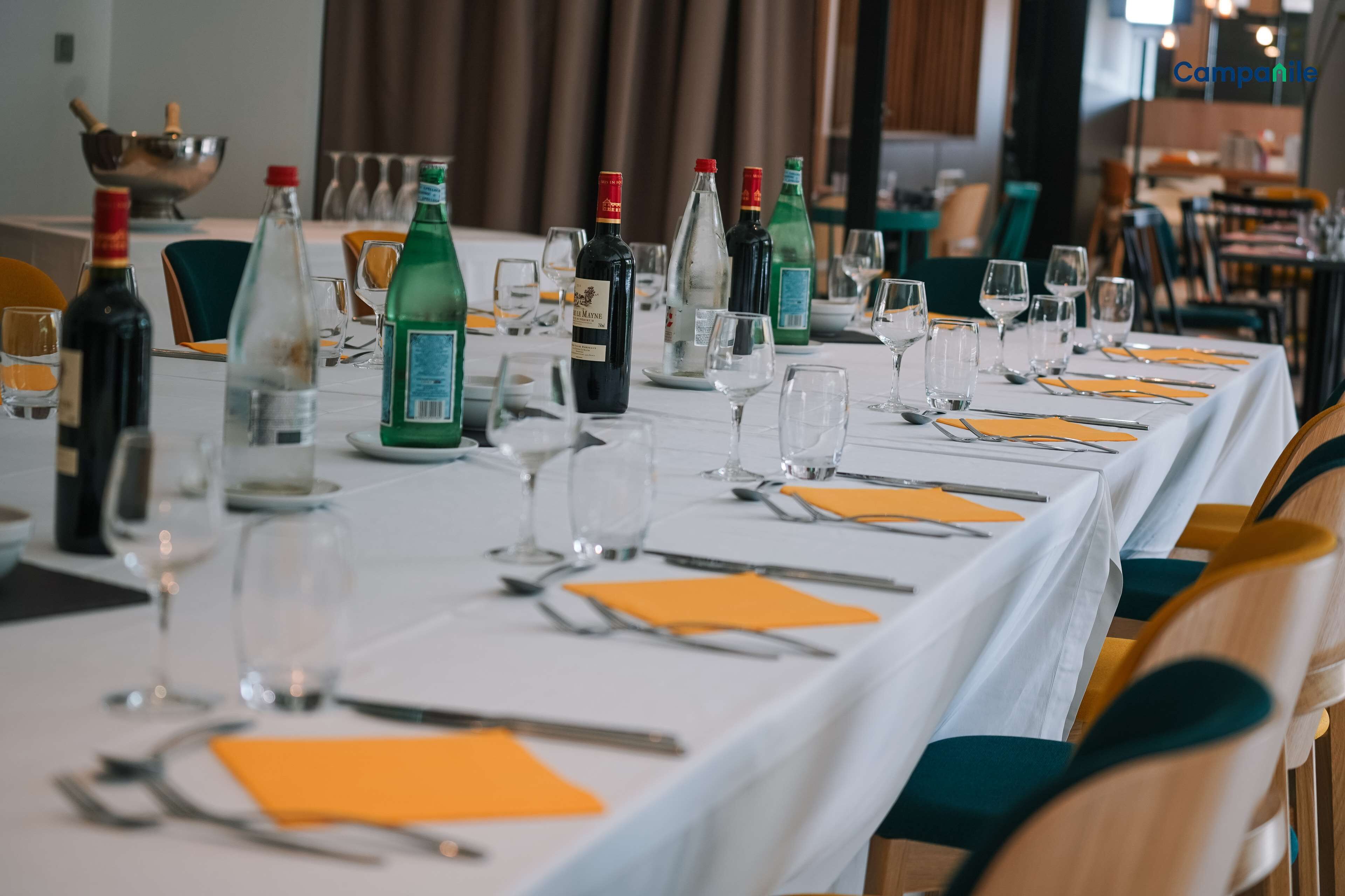 A restaurant table set with wine bottles, glasses, and cutlery.