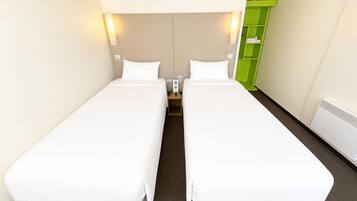 Una habitación de hotel con dos camas individuales, una mesita de noche con lámpara y un mueble de almacenamiento verde.