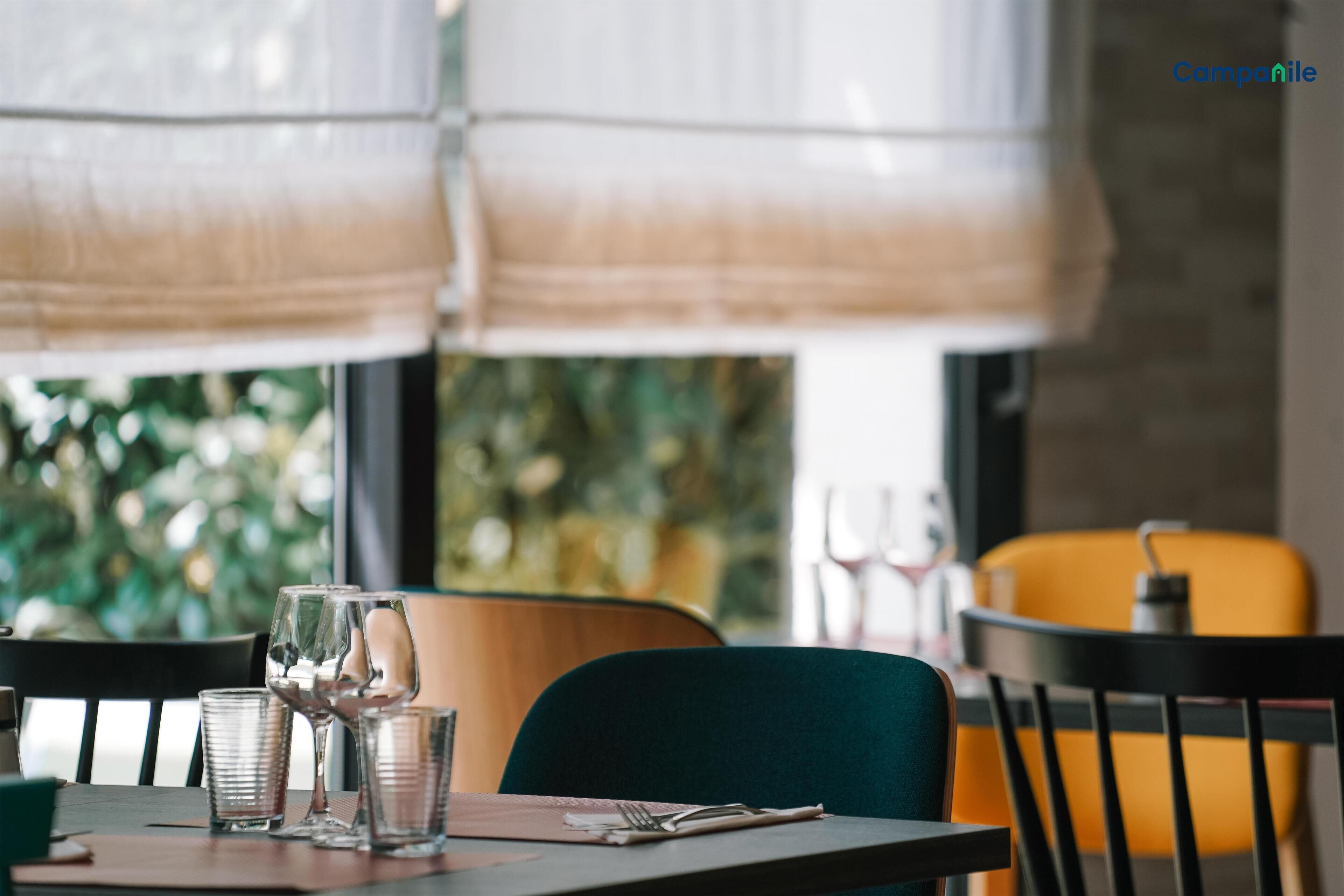 Un coin repas avec une table dressée pour deux personnes, comprenant des verres à vin et des couverts.