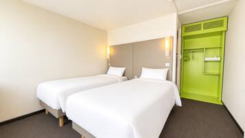 Een hotelkamer met twee enkele bedden, een groene garderobe en een lichtkleurig tapijt.