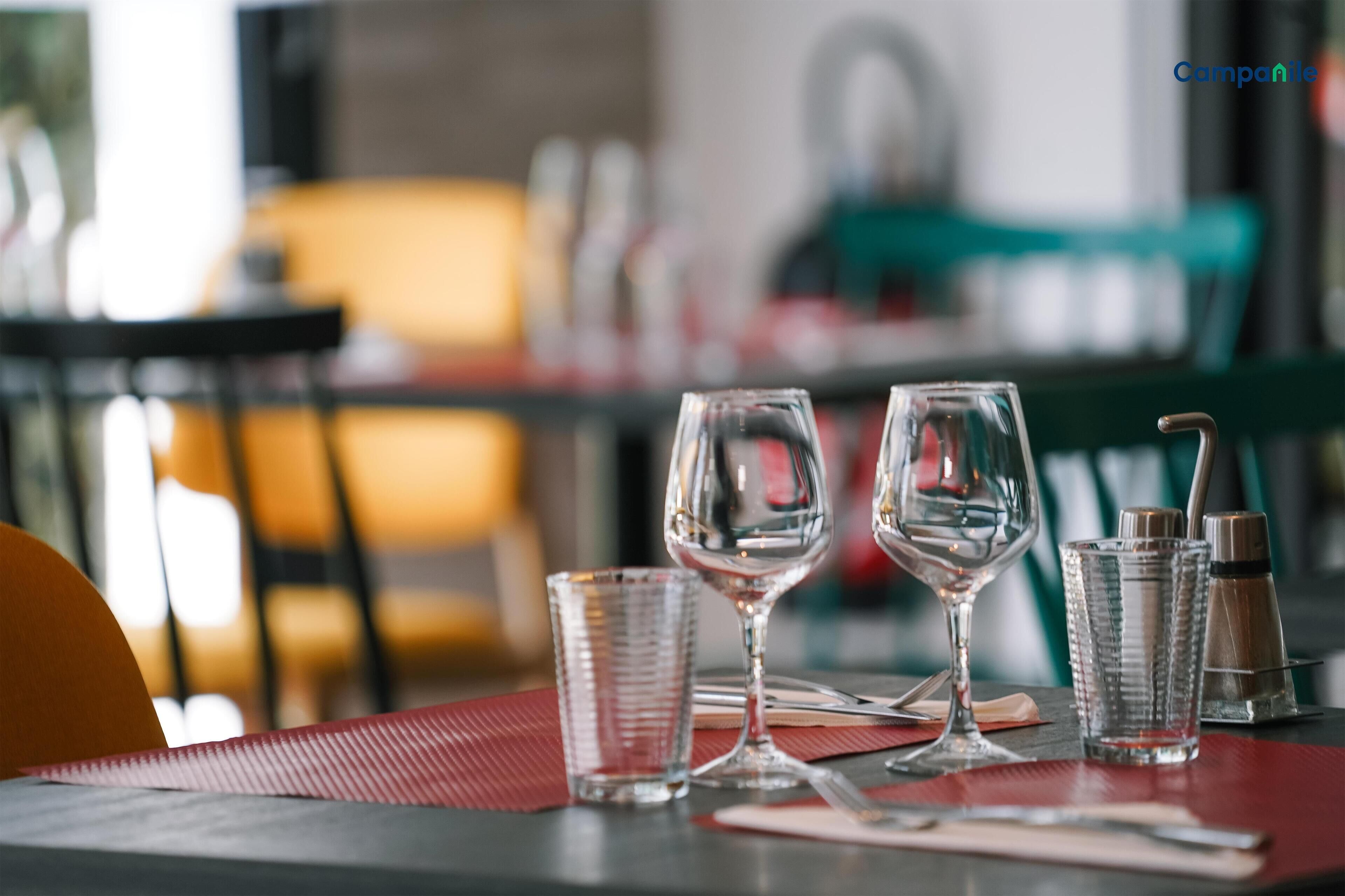 Una mesa servida con dos copas de vino, un vaso de agua y un salero y pimentero.