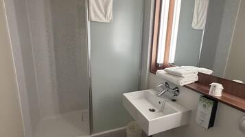 Une salle de bain avec une douche à parois de verre, un lavabo blanc et des toilettes.