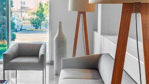A modern living room with a sofa, a chair, a floor lamp, and a vase. - City Express by Marriott Celaya Parque (Celaya)