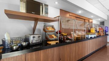Una cocina moderna con mostrador de madera, un tostador, una cesta de pan y diversos electrodomésticos.