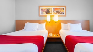 A hotel room with two beds, a wooden headboard, a red throw blanket, a nightstand with a phone, and a painting on the wall. - City Express by Marriott Celaya Parque (Celaya)