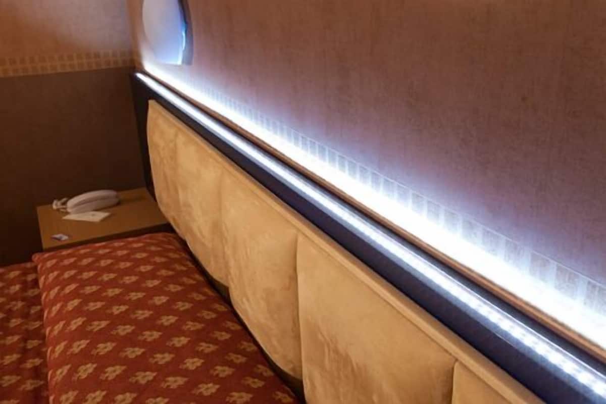 A hotel room with a bed, a bedside table with a telephone, and a window with blinds.