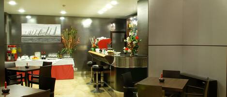 A modern restaurant interior with marble flooring, dark wooden tables and chairs, a bar area with stools, and a decorative plant centerpiece.
