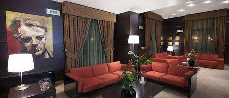 A modern hotel lobby with a red sofa set, a coffee table, a lamp, and a painting on the wall.