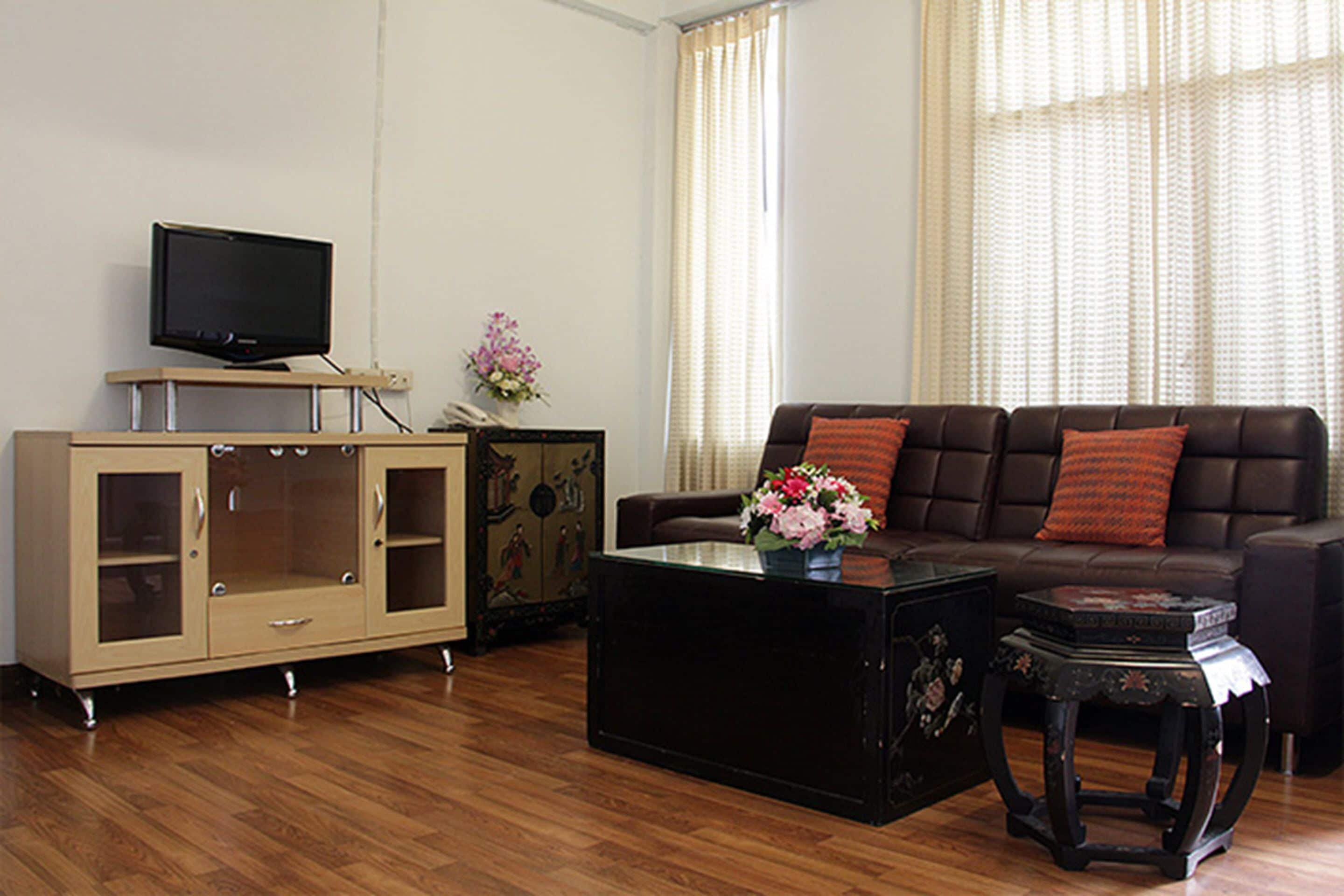 A living room with a sofa, a coffee table, a cabinet, and a television.