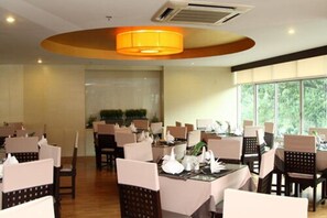 A dining area with round tables, chairs, and a central light fixture. - Maninarakorn Hotel (Chiang Mai)