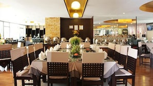 Un restaurant doté de nombreuses tables et chaises, d’un mur décoratif central et d’un plafond pourvu d’un éclairage encastré.