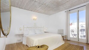 A bedroom with a large bed, a bedside table, a lamp, a mirror, and a view of the outside balcony. - Can Beia Hostal Boutique (Sant Antoni de Portmany)