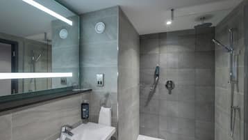 Un baño moderno con cabina de ducha de vidrio, un lavabo blanco y un espejo grande.