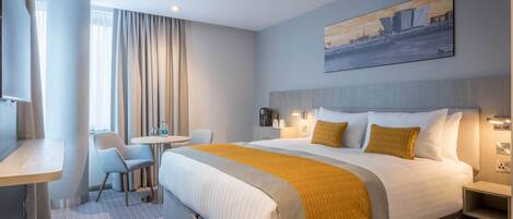 Una habitación de hotel con una cama grande, un escritorio, una silla y una mesita.