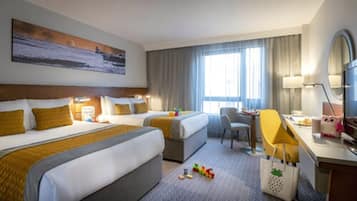 Ein Hotelzimmer mit zwei Betten, einem Schreibtisch, einem Sessel, einem Fernseher und einem Bild an der Wand.