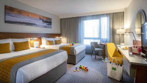 A hotel room with two beds, a desk, a chair, a TV, and a painting on the wall. - Maldron Hotel Parnell Square Dublin City (Dublin)
