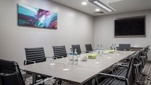 A conference room with a long table, black chairs, a projector screen, and a large abstract painting on the wall. - Maldron Hotel Parnell Square Dublin City (Dublin)