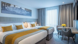 A hotel room with two beds, a dining table with chairs, a TV, and a large window with curtains. - Maldron Hotel Parnell Square Dublin City (Dublin)