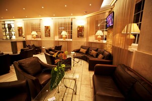 Una hall con divani in pelle, una reception e un televisore a parete.