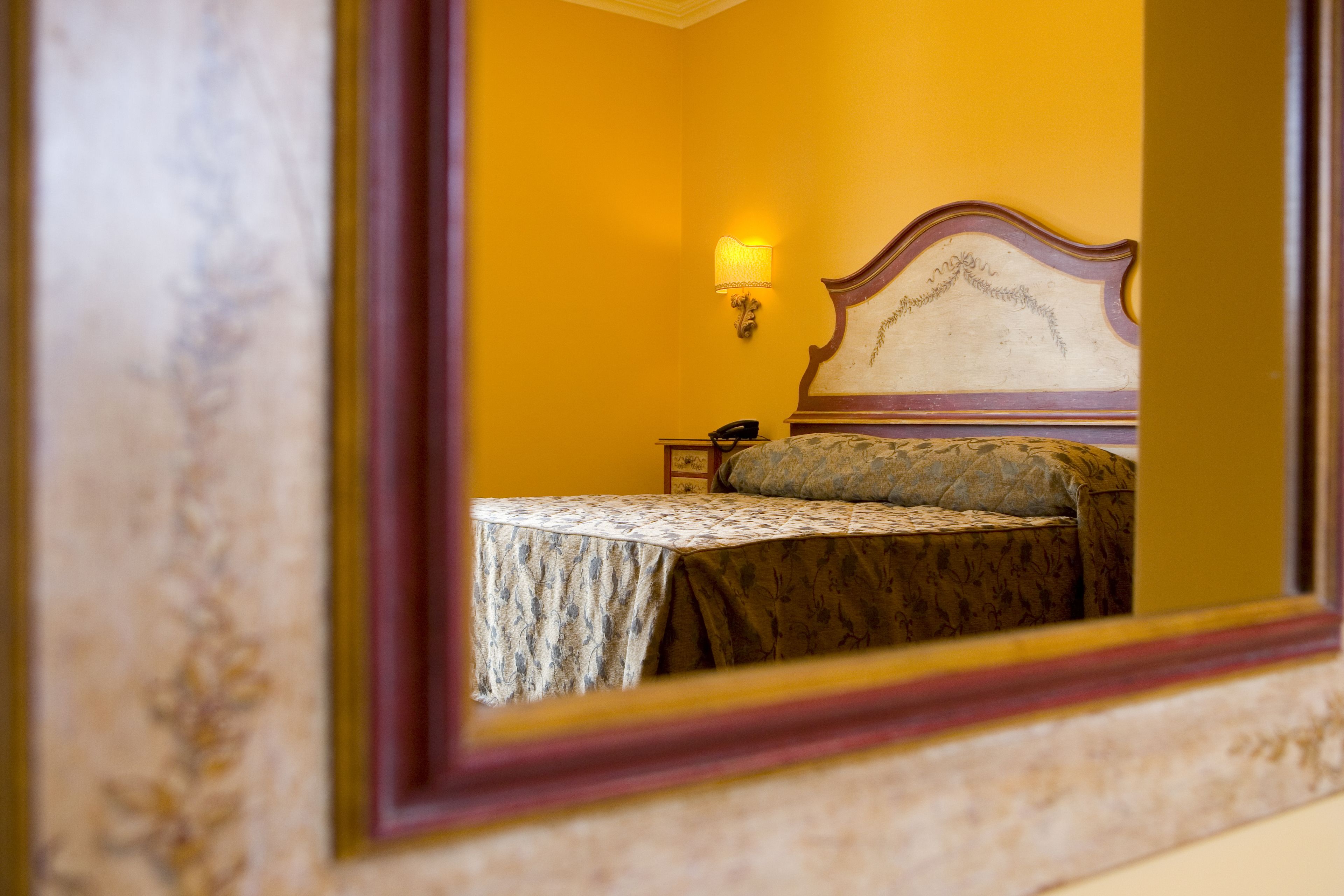 A bedroom with a bed, a nightstand, and a wall-mounted lamp.