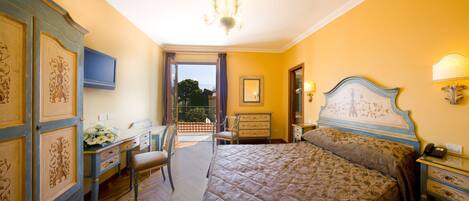 Habitación de hotel con cama, escritorio, silla, cómoda, espejo y candelabro.
