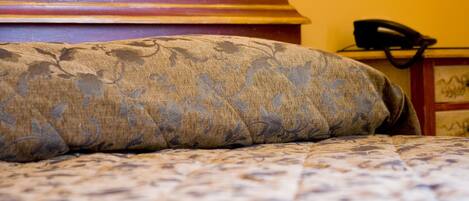 A bed with a patterned bedspread and a headboard with a decorative design.