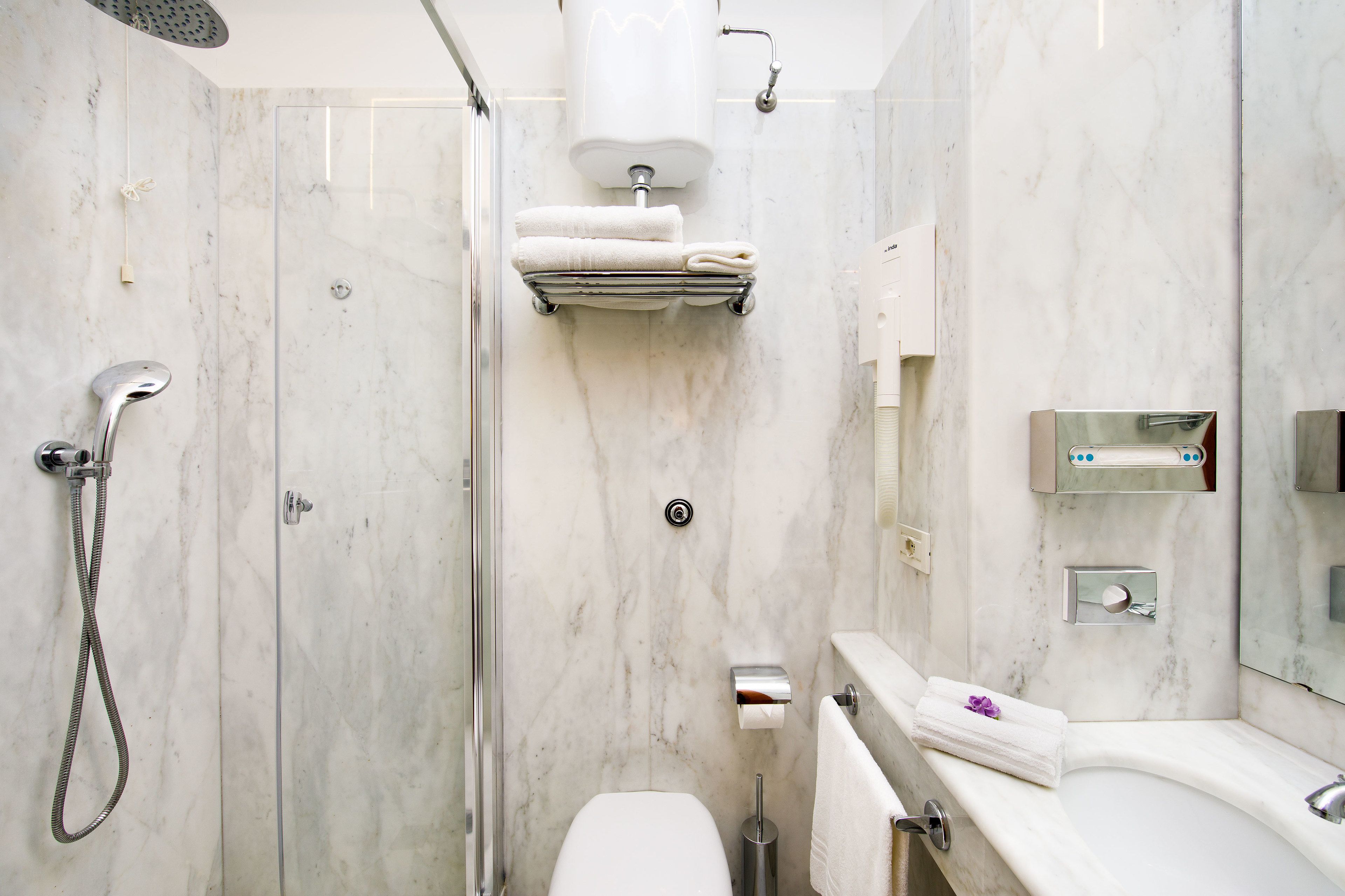 A modern bathroom with a glass-enclosed shower, a toilet, and a sink with a mirror.