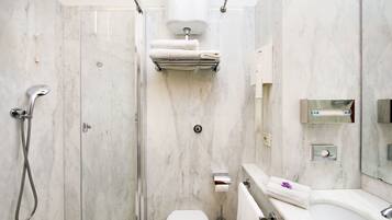 A modern bathroom with a glass-enclosed shower, a toilet, and a sink with a mirror.