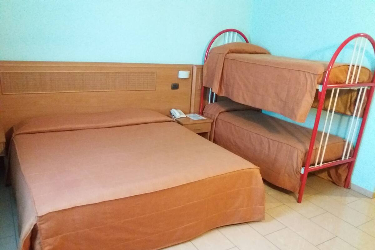 A bunk bed with a wooden headboard and a nightstand with a phone.