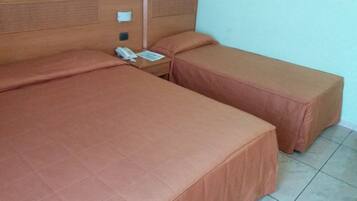 Ein Hotelzimmer mit einem großen Bett, einem kleineren Bett und einem Nachttisch mit Telefon und Papieren.