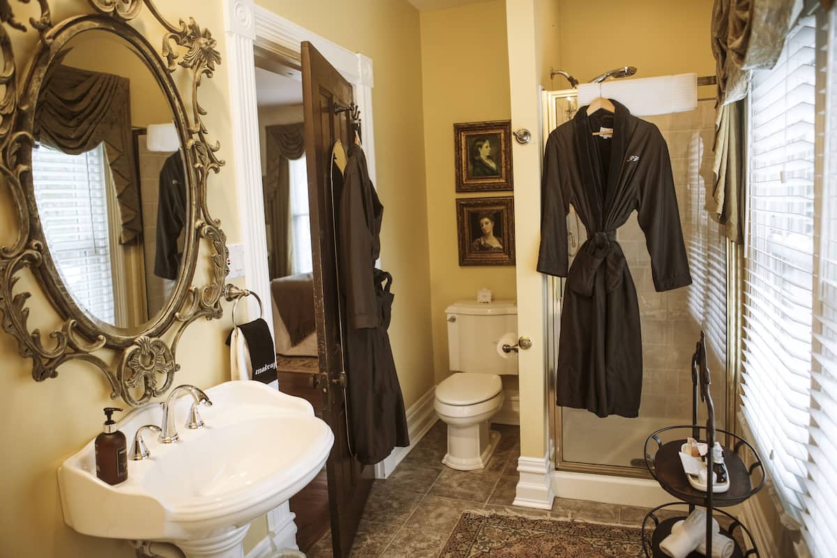 A bathroom with a white sink, a large ornate mirror, a toilet, and a shower area.