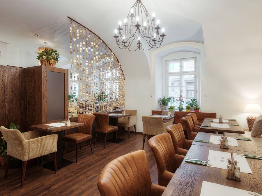 A restaurant with wooden furniture, a chandelier, and a large window.