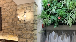 Un salon chaleureux avec un mur en pierre, un canapé confortable, un fauteuil et une petite table.