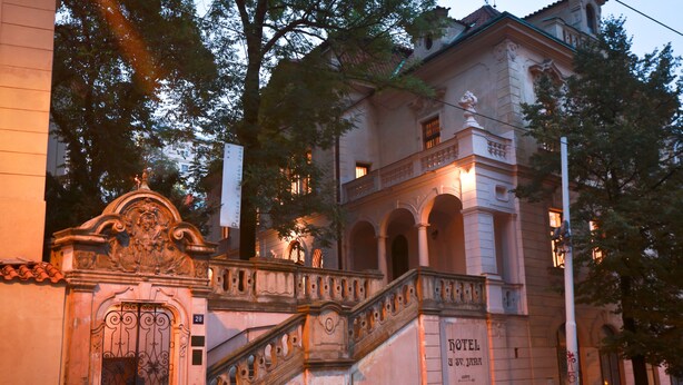 Ein historisches Gebäude mit einem prunkvollen Eingang, einer Treppe und einem Schild, das es als Hotel kennzeichnet.