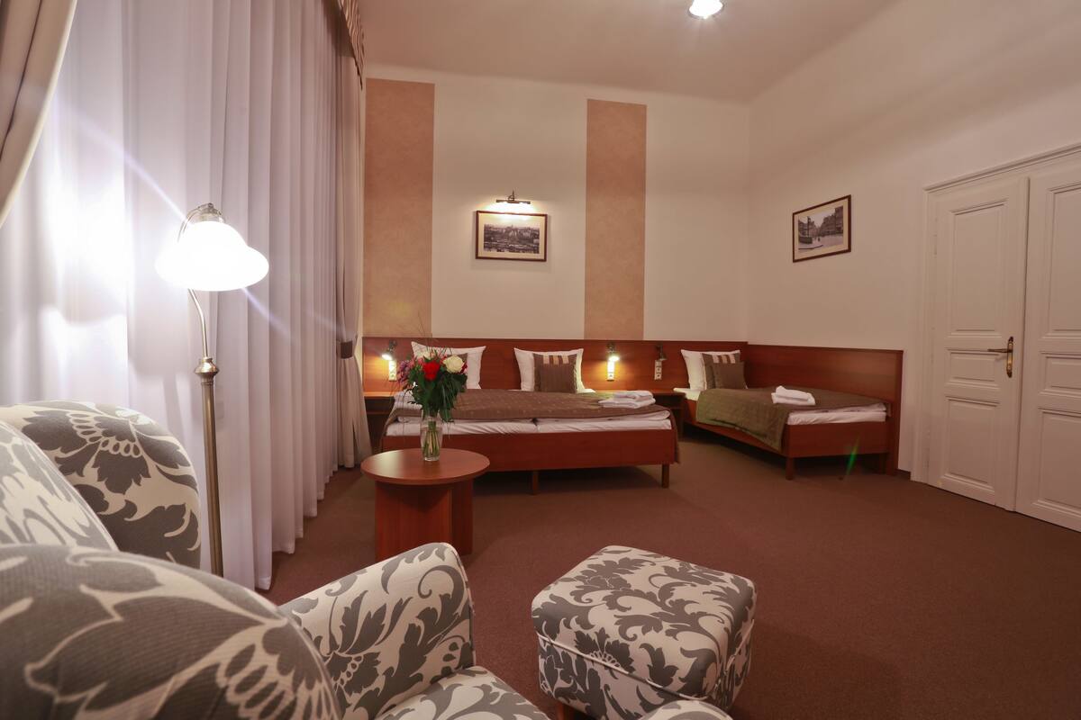 Habitació d'hotel amb un llit, dos sofàs, una taula petita amb un vas i una làmpada.