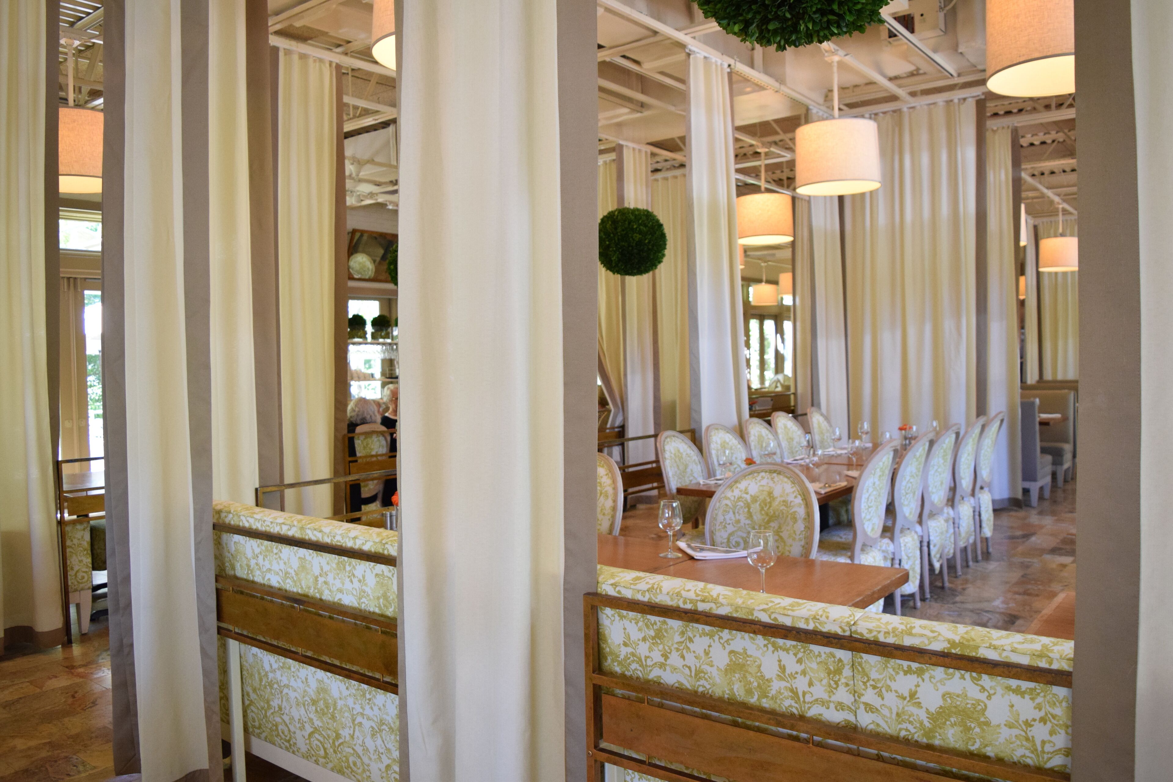 A dining area with a long wooden table set for a meal, surrounded by upholstered chairs with a floral pattern.