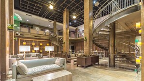A spacious lobby with a high ceiling, a central staircase, and multiple seating areas. - Proximity Hotel (Greensboro)