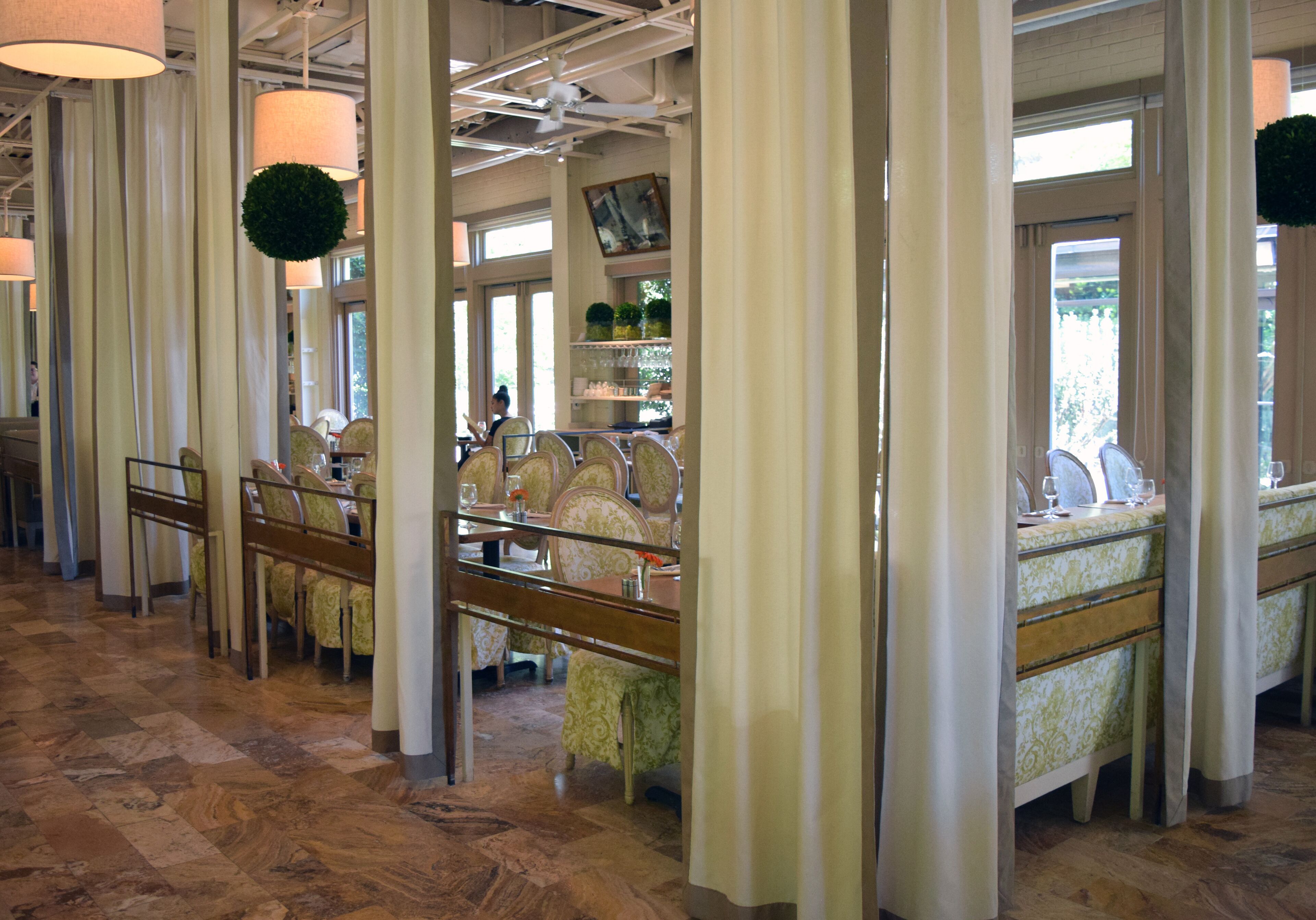 Un restaurant avec un sol à carreaux, de hauts plafonds et des plantes vertes suspendues.