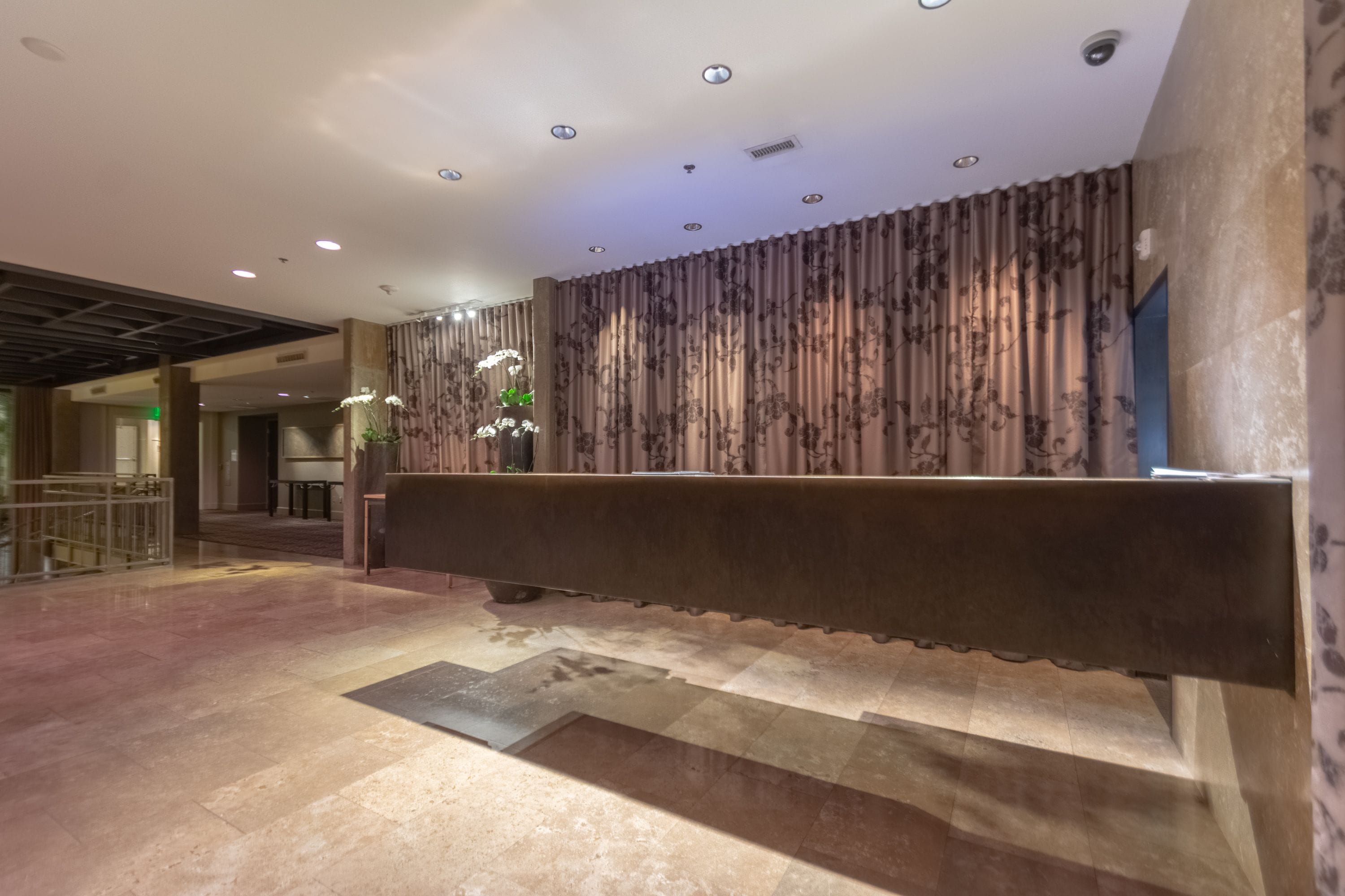 A reception area with a bench, patterned curtains, and a ceiling with recessed lighting.