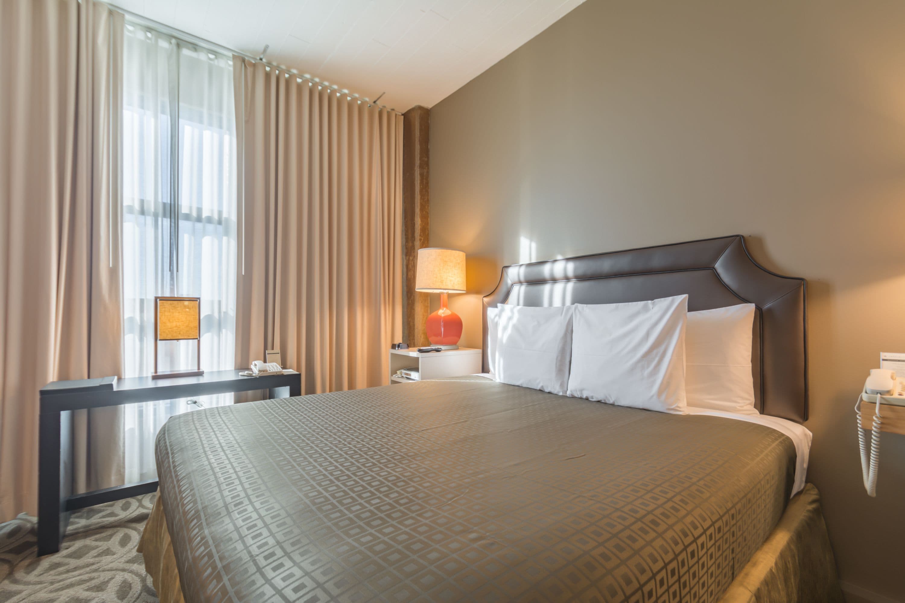Une chambre d ’hôtel avec un grand lit, une table de chevet, une lampe et un téléphone.