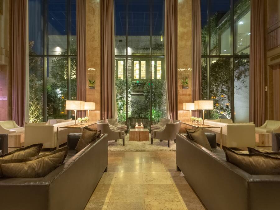 A spacious lobby with a central seating area, large windows, and a view of greenery outside.