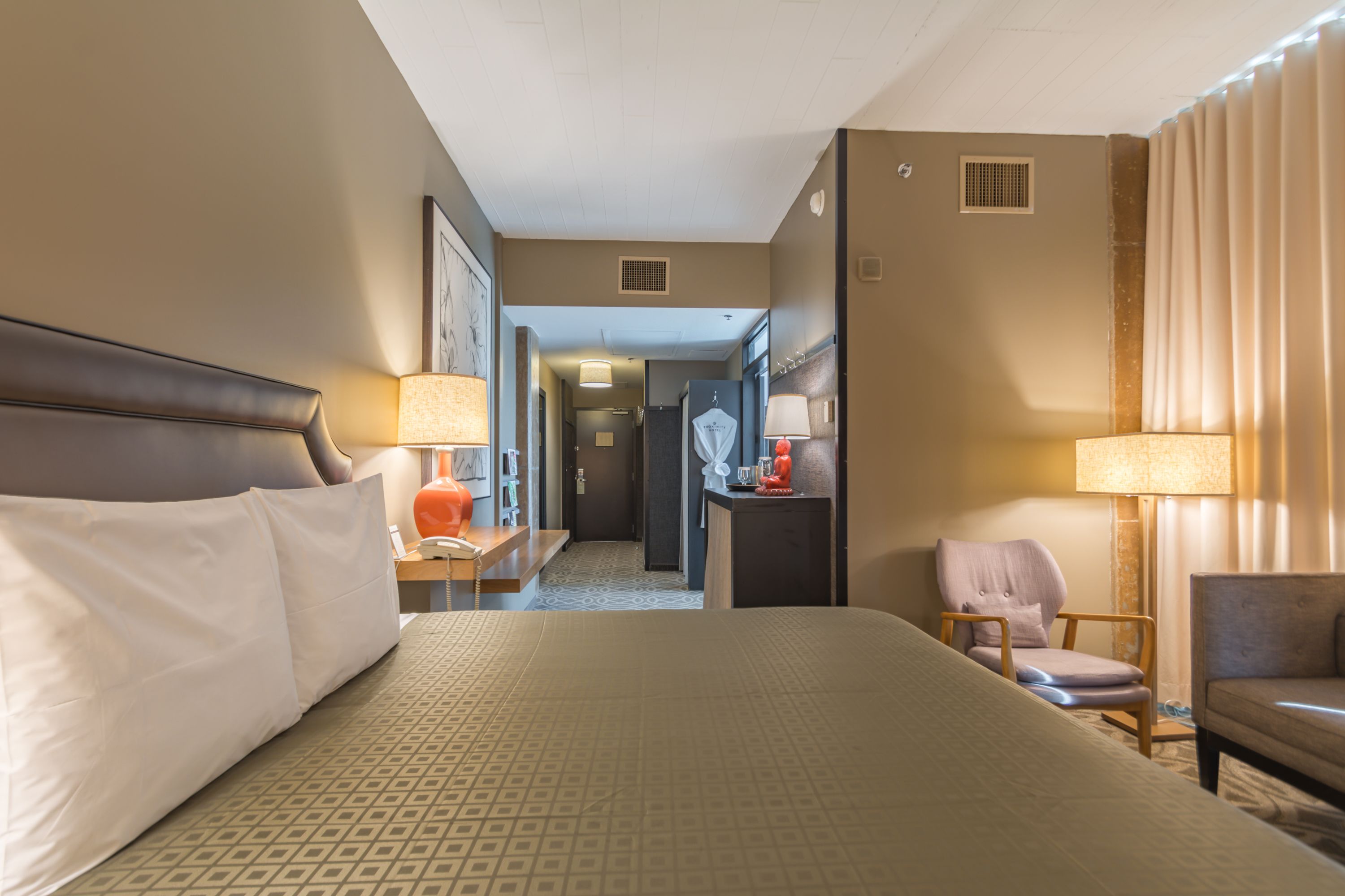 A hotel room with a large bed, two chairs, a desk, and a bathroom visible through an open door.