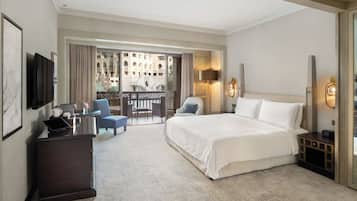 Une chambre d’hôtel avec un grand lit, un bureau avec un ordinateur portable, une chaise et un balcon donnant sur un immeuble.