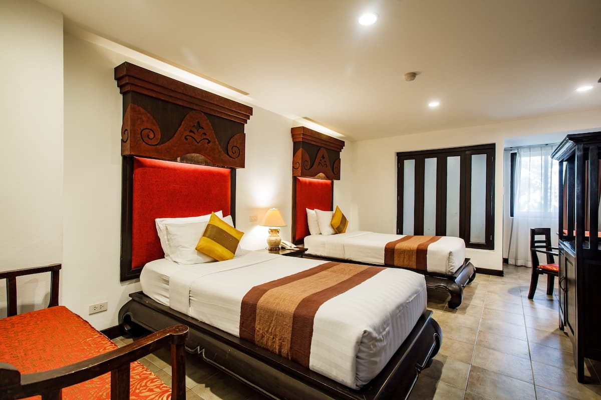 A hotel room with two beds, a desk, and a chair.