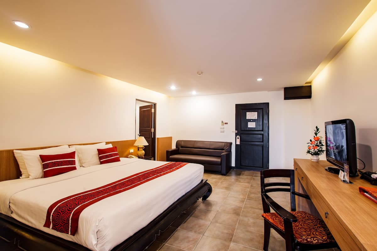 A hotel room with a bed, a desk, a chair, a television, and a door.